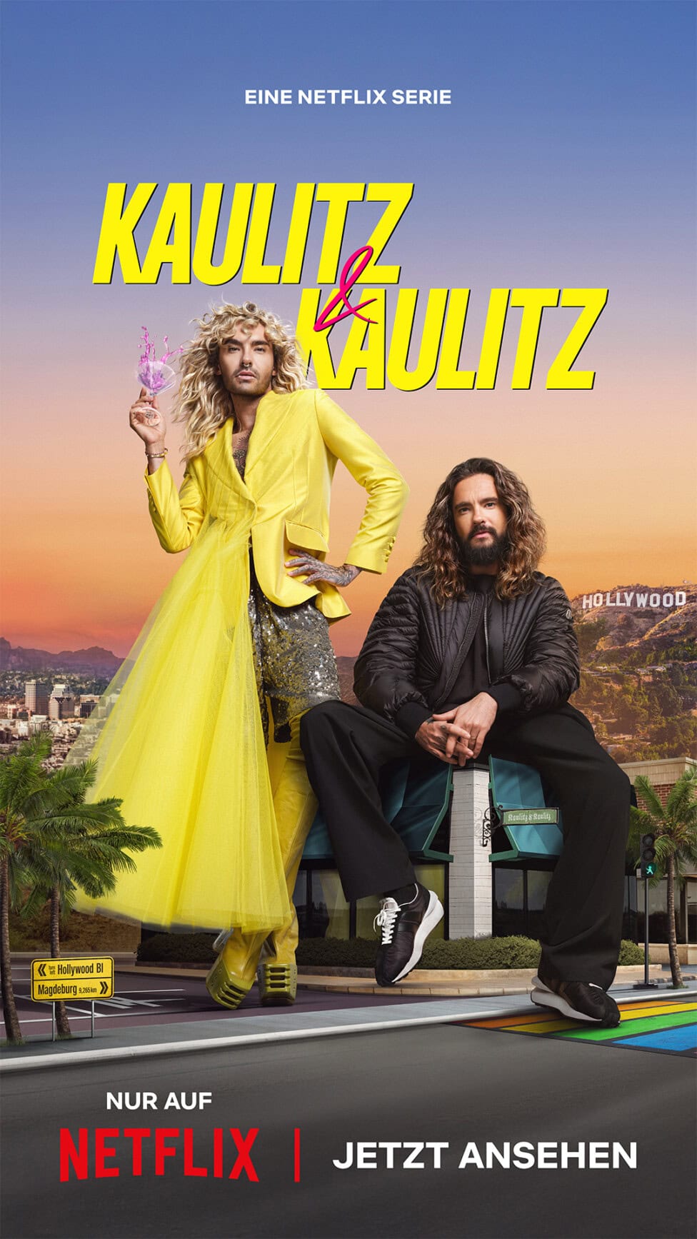 TV & Streaming Tipps im August – Special „Beliebteste Reality-Serie”: Plakat zur Netflix-Serie ‚Kaulitz & Kaulitz‘. Links steht Bill Kaulitz mit langen blonden Locken in einem auffälligen gelben Kleid und Blazer, er hält ein Glas in der Hand. Rechts sitzt Tom Kaulitz mit langen braunen Haaren und Bart in schwarzer Kleidung. Im Hintergrund ist das Hollywood-Zeichen und eine Stadtlandschaft. Unten steht: Nur auf Netflix, Jetzt ansehen