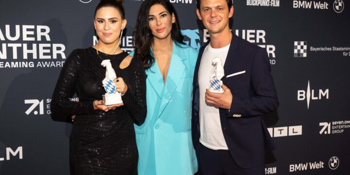 Preisträger:innen Salwa Houmsi (links) und Jo Schück (rechts) mit der Panther Trophäe und in der Mitte Laudatorin Samira el Ouassil