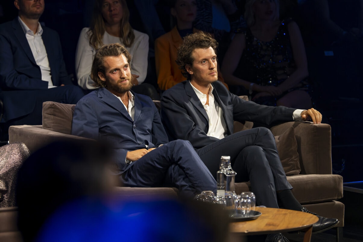 Jono und Benji Bergmann (c) Medien.Bayern - Ralf Wilschewski Jono und Benji Bergmann sitzen beim Blauen Panther 2022 auf einer Couch. Im Hintergrund ist vereinzelt das Publikum zu sehen. (c) Medien.Bayern - Ralf Wilschewski