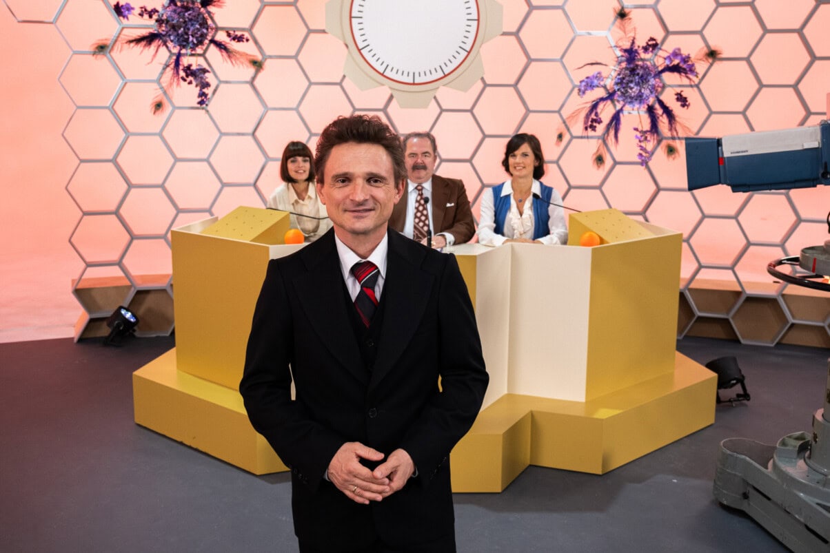 Rosenthal_c_ZDF/Ella Knorz TV & Streaming Tipps Oktober: Moderator in einem Fernsehstudio, Teilnehmer:innen an einem Pult im Hintergrund