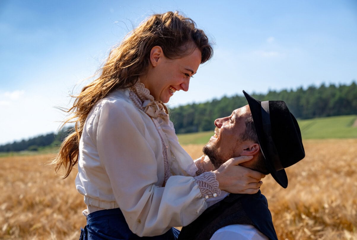 Oktoberfest 1905 ARD Liebespaar im Feld mit Sonnenbrille und Hut, romantisches Umarmung im Freien.