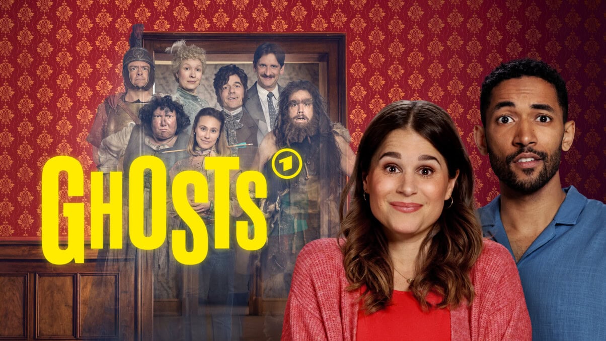 "Ghosts" ab 14. März 2025 als Download erhältlich Großer gelber Schriftzug "GHOSTS" mit dem Logo von DAS ERSTE. dahinter stehen sieben Personen, die Kleider aus verschiedenen historischen Epochen tragen. Die Personen sehen transparent aus. Auf der rechten Seite stehen die beiden Hauptfiguren, ein Paar, das freundlich, aber etwas verwirrt in die Kamera sieht.