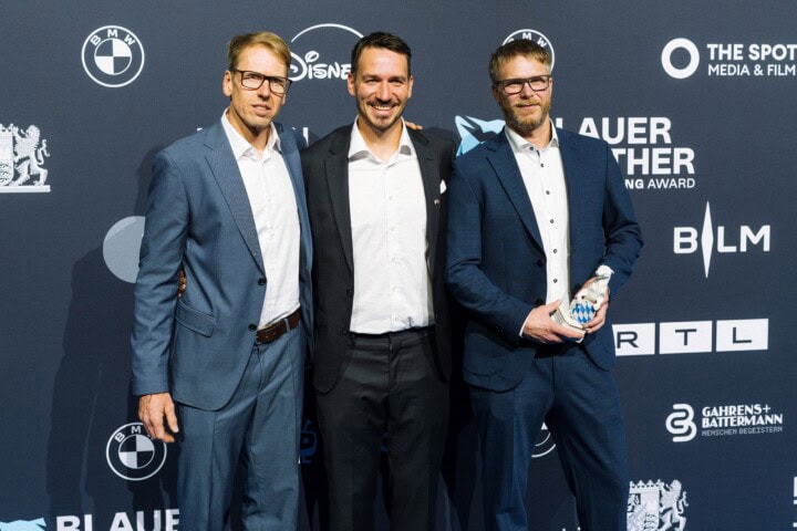 Franz Hinterbrandner (l.) und Max Reichel (r.) erhalten den „Blauer Panther – TV & Streaming Award“ 2026 für das „Beste Factual-Entertainment-Format“ für Produktion und Kamera in „In höchster Not – Bergretter im Einsatz“ (Timeline Production im Auftrag des Bayerischen Rundfunks für die ARD Mediathek) ausgezeichnet. Laudator Felix Neureuther (Mi.) freut sich mit den Gewinnern.