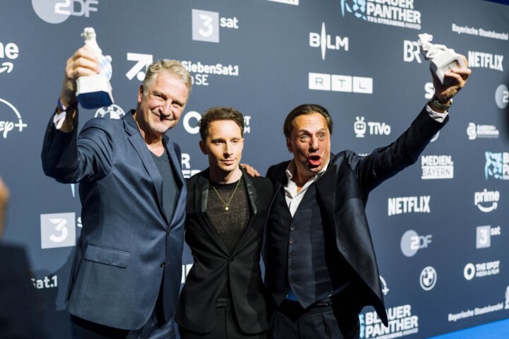 Michael Souvignier (l.) und Till Derenbach (r.) erhalten den „Blauer Panther – TV & Streaming Award“ 2026 für das „Beste Dokumentationsdrama“ und die herausragende Produktionsleistung in „Nürnberg 45 – Im Angesicht des Bösen“ (Zeitsprung Pictures GmbH in Koproduktion mit der Spiegel TV GmbH, im Auftrag von NDR, BR, SWR, WDR, RBB, MDR, HR, SR und Radio Bremen für die ARD). Laudator Jonathan Berlin (Mi.) freut sich mit den Gewinnern.